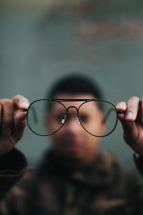 Man holding eye glasses and looking through them from a distance