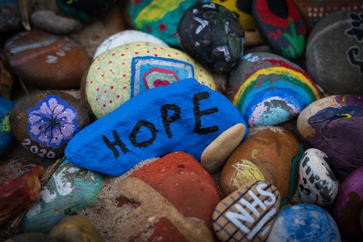 Rocks painted with rainbows, flowers, patterns and the word HOPE