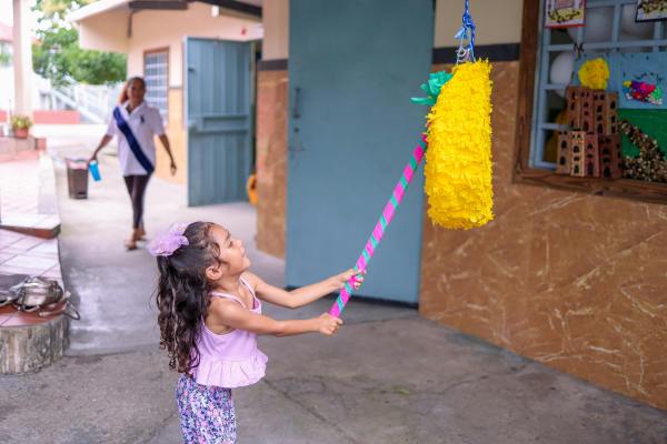 small girl hitting a pinata with a bat