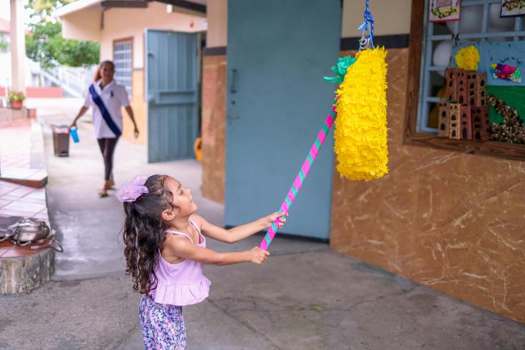 small girl hitting a pinata with a bat